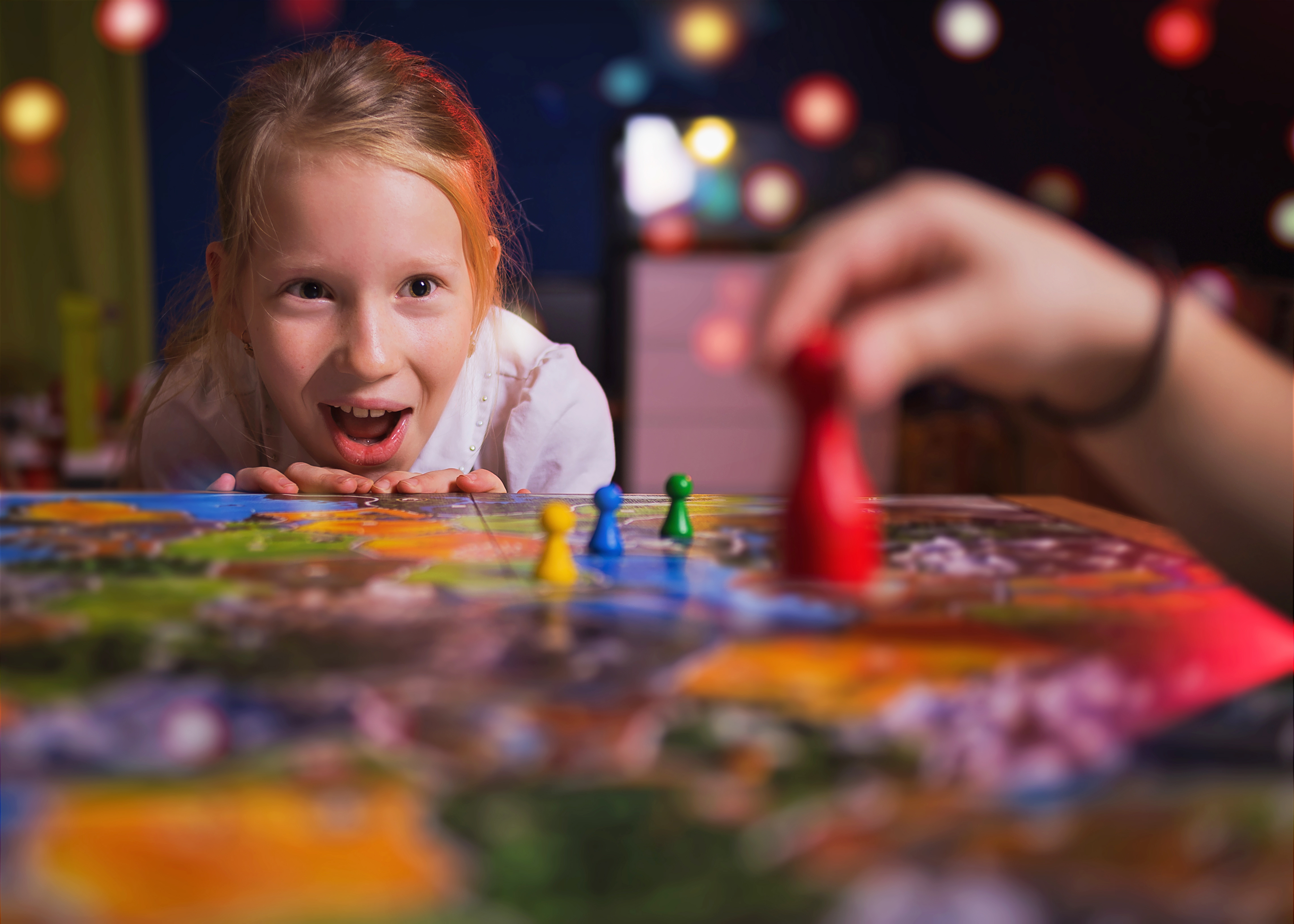 A girl sitting across a table playing a board game